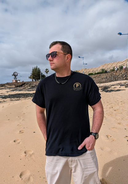 Man wearing sunglasses and a black Leonidas of Sparta Original t-shirt with the logo on a beach