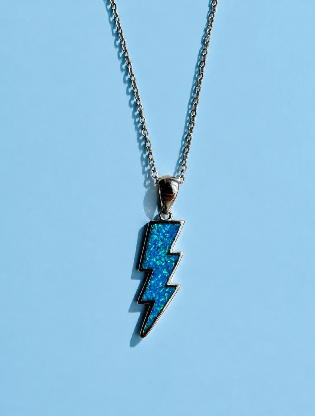 Blue Zeus thunderbolt necklace with lightning bolt pendant on a silver chain, inspired by Greek mythology.